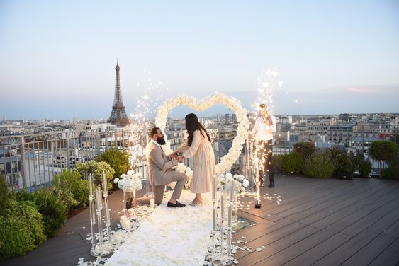 Shooting de demande en mariage sur un rooftop parisien avec une arche cœur et un décor romantique